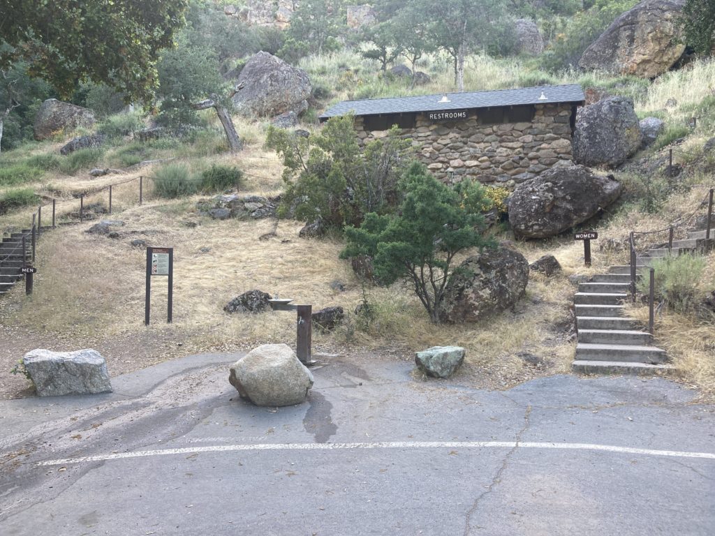 Brick Walled Bathroom in the Hill with Trees and Rocks Behind