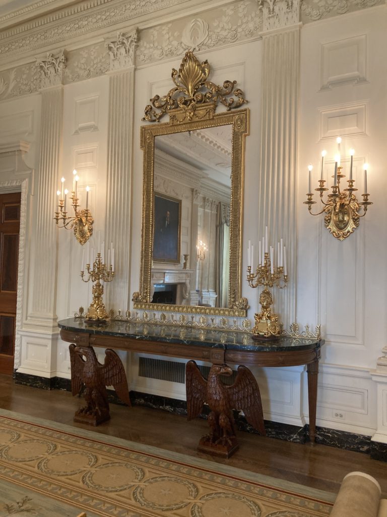 Gold Framed Mirror Hanged Above the Brown Table with Candelabras