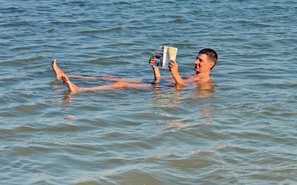 Men floating in the Dead Sea reading a book