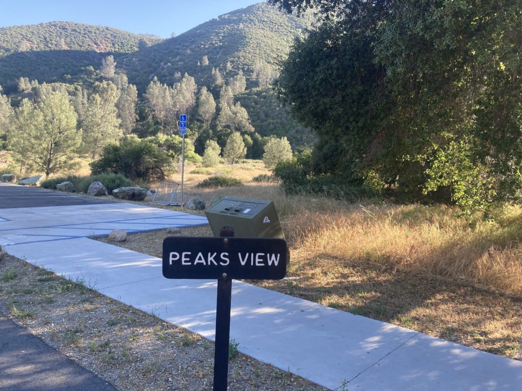 Peaks View Signboard with Trees and Mountain in the Background